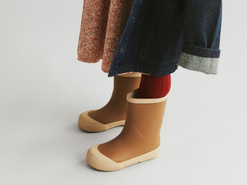 gummistøvler på et barn med kjole