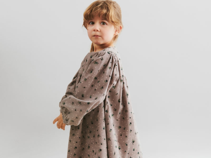 Lille pige i en mønstrede kjole i farven lyserød