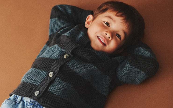 Lille dreng i stribet strik cardigan i farverne mærkegrå og blå